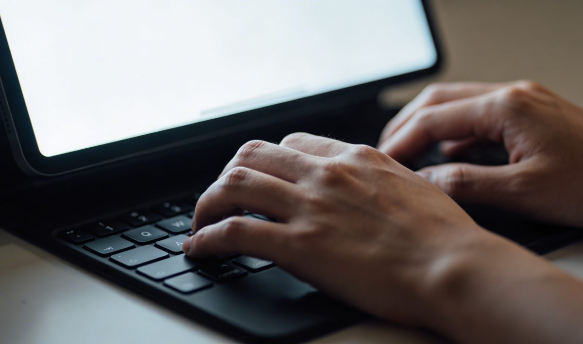 Personne tapant sur un clavier devant ecran lumineux