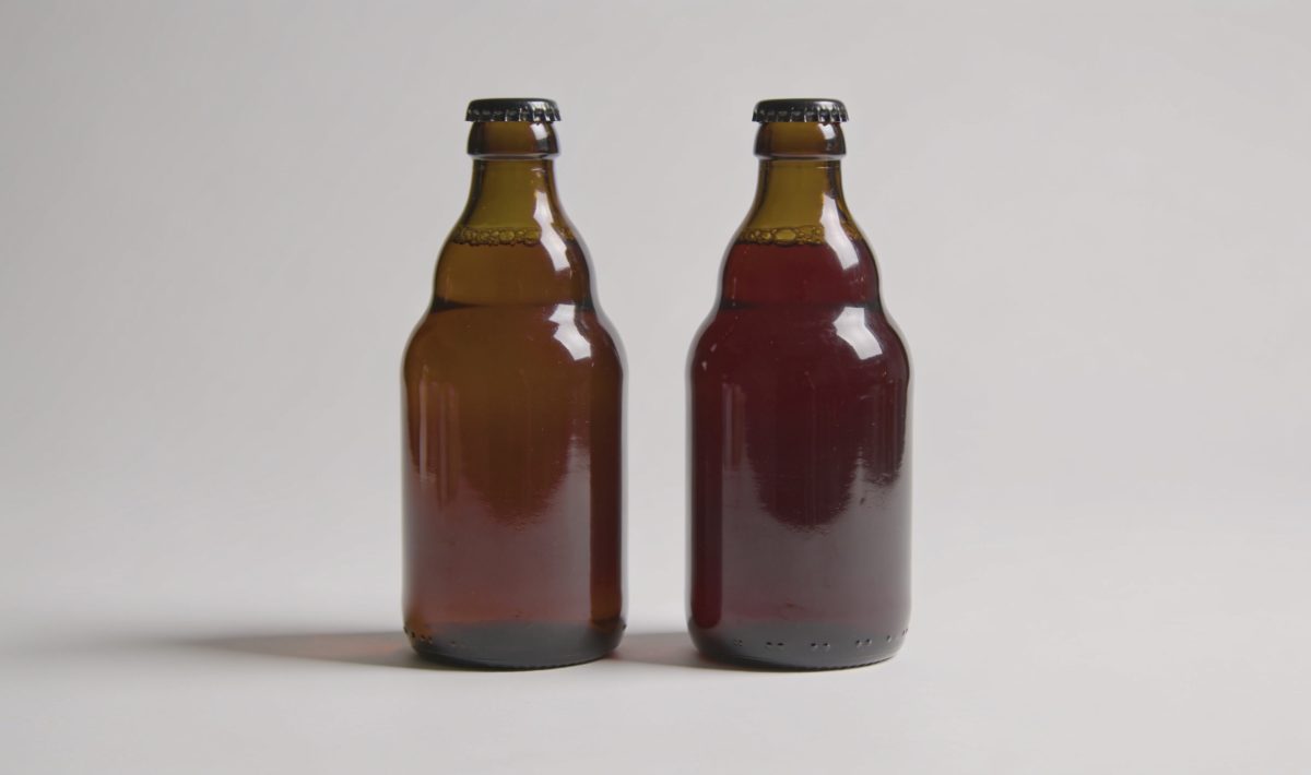 Deux bouteilles identiques placees cote a cote sur surface blanche