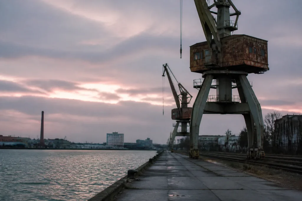 Grues rouillees surplombant un quai desert au crepuscule