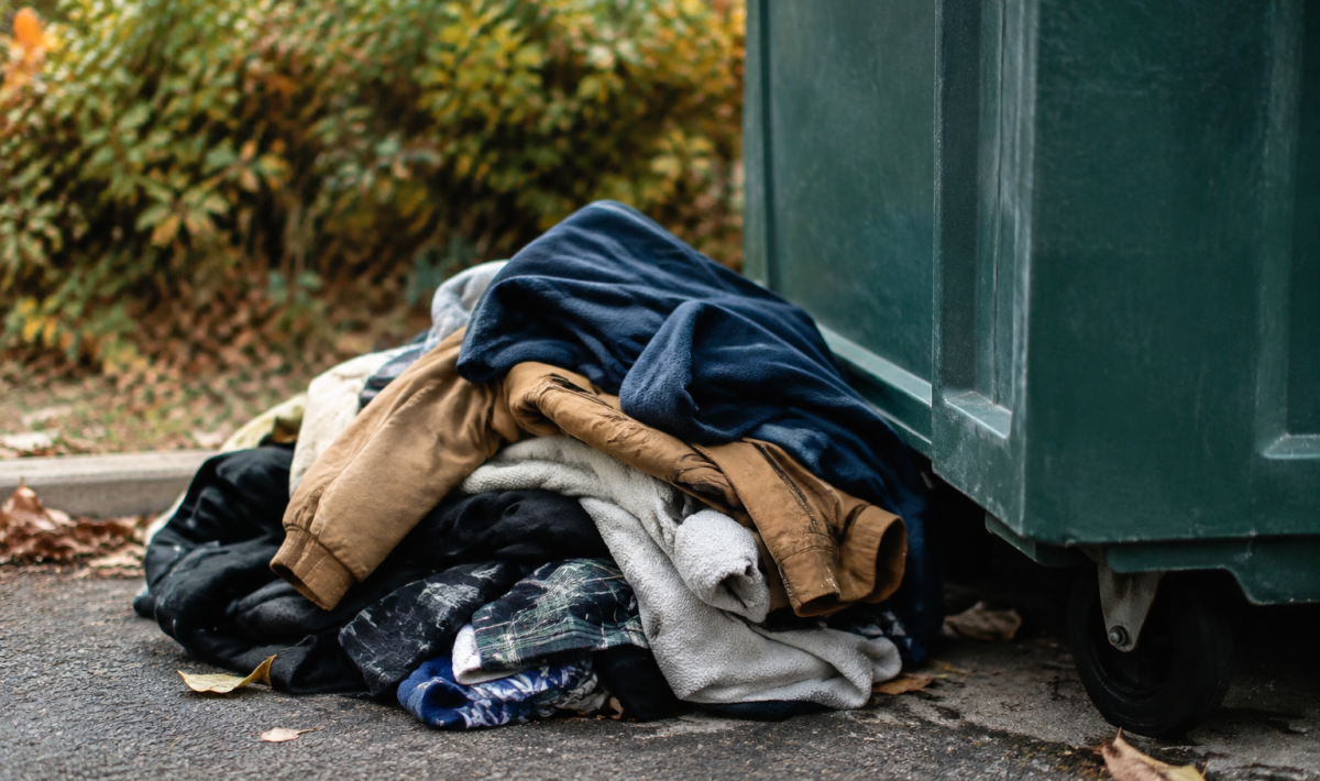 Vetements usages empiles pres du bac collecte